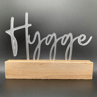 Elegant Hygge Schriftzug in transparenter Acryl-Optik auf Holzsockel, ideal für Dekorationen von Easy-Sticks. Perfekt für ein stilvolles Zuhause - Easy-Sticks Acryl Aufsteller - Hygge.