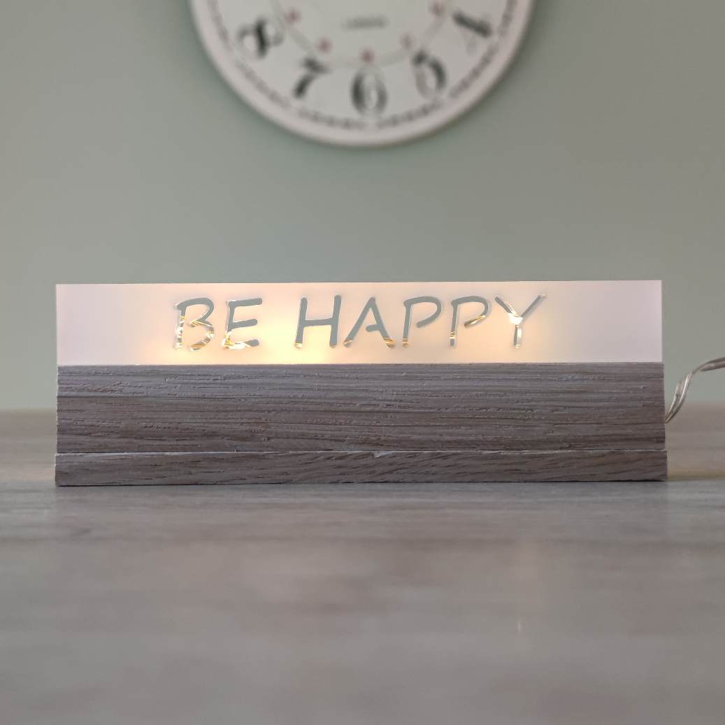 Eleganter Acryl-Easy-Stick 'BE HAPPY' von Easy-Sticks, leuchtet warm auf einem Tisch und schafft eine einladende Atmosphäre.