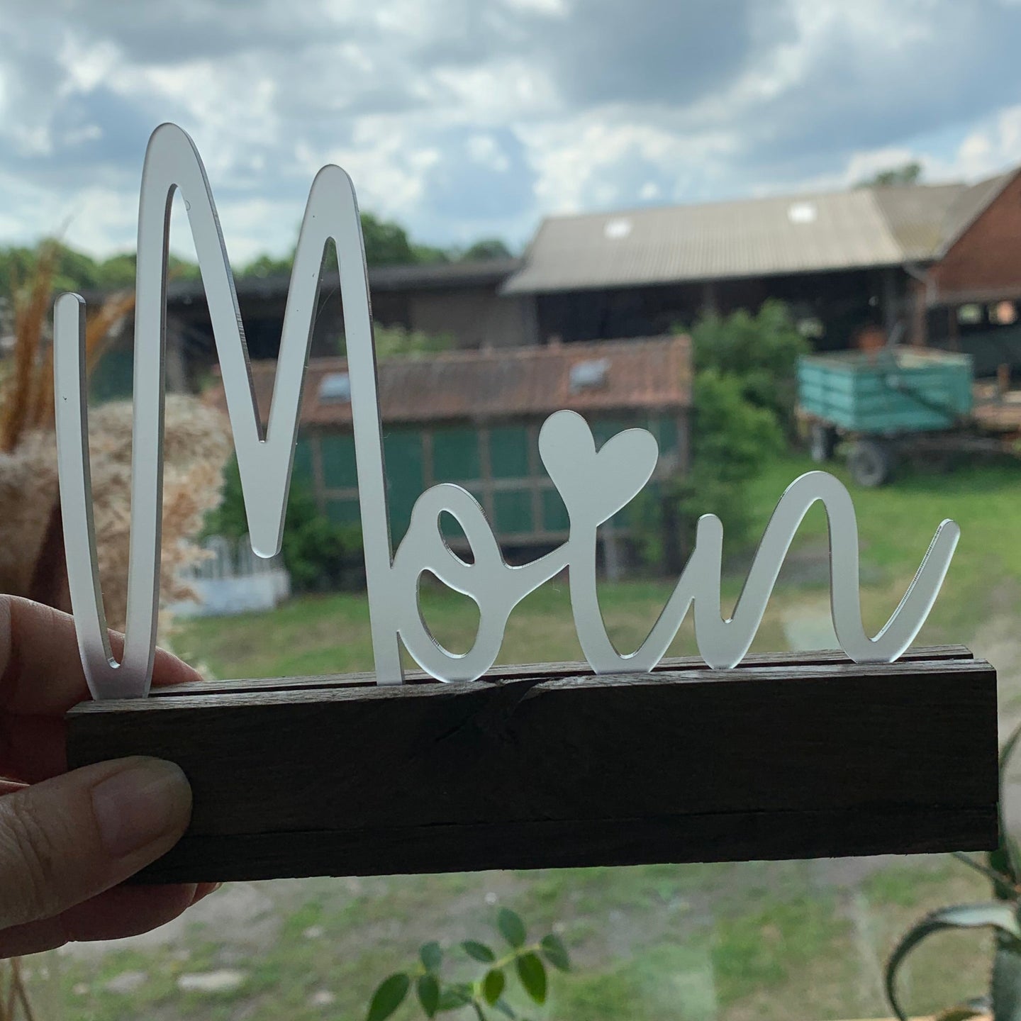 Der elegante 'Moin' Schriftzug von Easy-Sticks ist stilvoll auf einem Holzstamm platziert. Perfekt als dekorativer Akzent für dein Zuhause oder als Geschenkidee.
