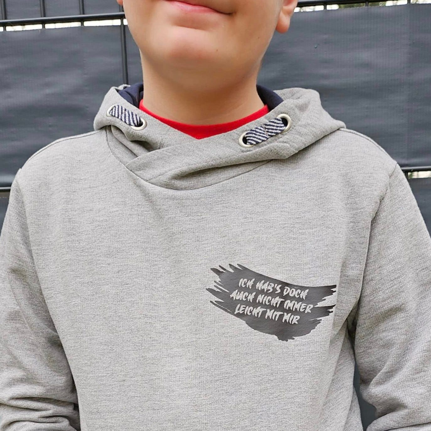 Junge trägt ein graues Sweatshirt mit dem Aufdruck "Ich hab's doch auch nicht immer leicht mit mir" von easy-sticks, ideal für kreative DIY-Projekte.