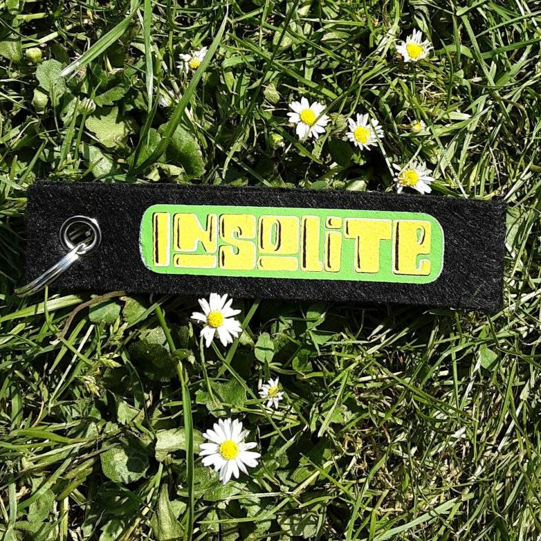 Schlüsselanhänger aus schwarzem Material, bedruckt mit dem Schriftzug 'Insolite' in leuchtendem Grün, perfekt für einzigartige Accessoires von easy-sticks.