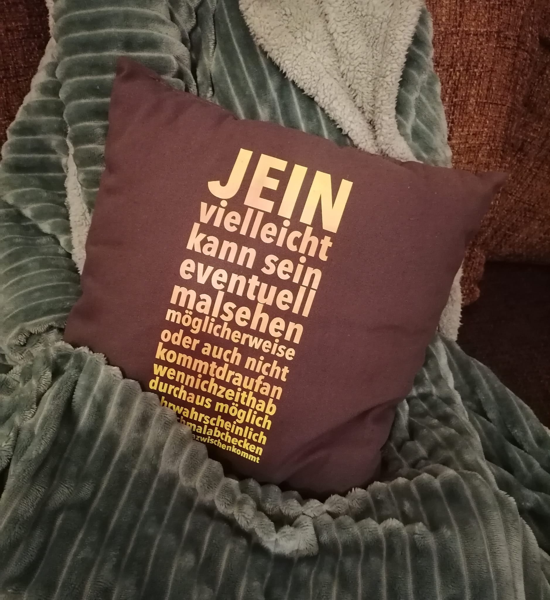 Kissenbezug mit dem Spruch "JEIN vielleicht kann sein" in lebhaften Farben, der auf einem gemütlichen Sofa liegt, angeboten von easy-sticks. Ideal für persönliche Akzente in deinem Wohnraum.