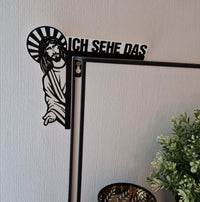 Dekoratives Wandobjekt "Jesus, ich sehe das" von easy-sticks, das auf einem Spiegel sitzt, umgeben von einem Topf mit Pflanzen, in stilvollem, modernem Design.