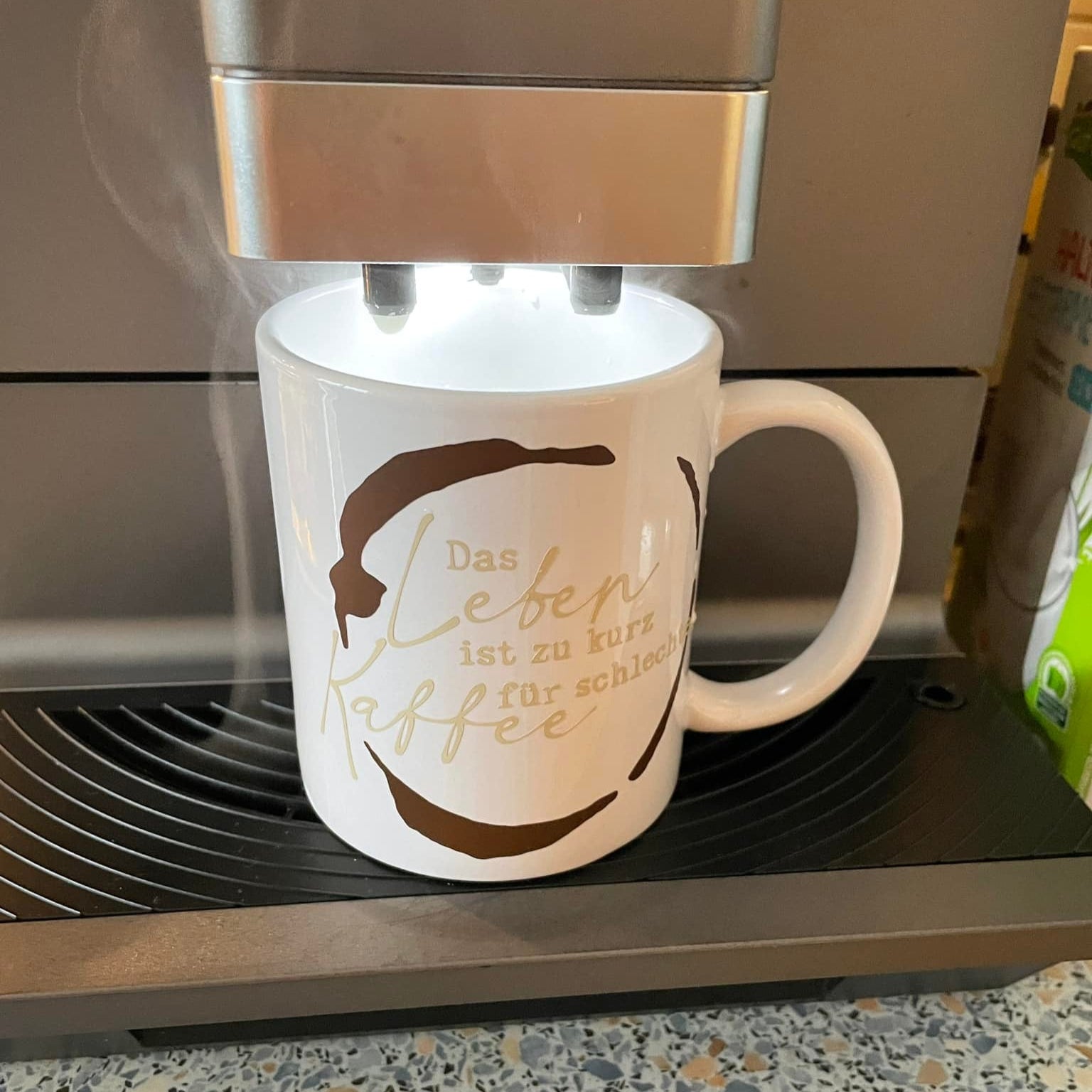 Eine dampfende Kaffeetasse unter einer Kaffeemaschine mit dem Spruch 'Das Leben ist zu kurz für schlechten Kaffee' - ein tolles Beispiel aus der 'Kaffee Sprüche Plotterdatei' von easy-sticks.