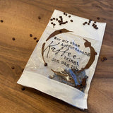 Eine Packung mit Kaffeebohnen neben einer durchsichtigen Verpackung, die den Spruch 'Wer mir ohne Aufforderung Kaffee bringt, den mag ich' zeigt - inspiriert durch die 'Kaffee Sprüche Plotterdatei' von easy-sticks.