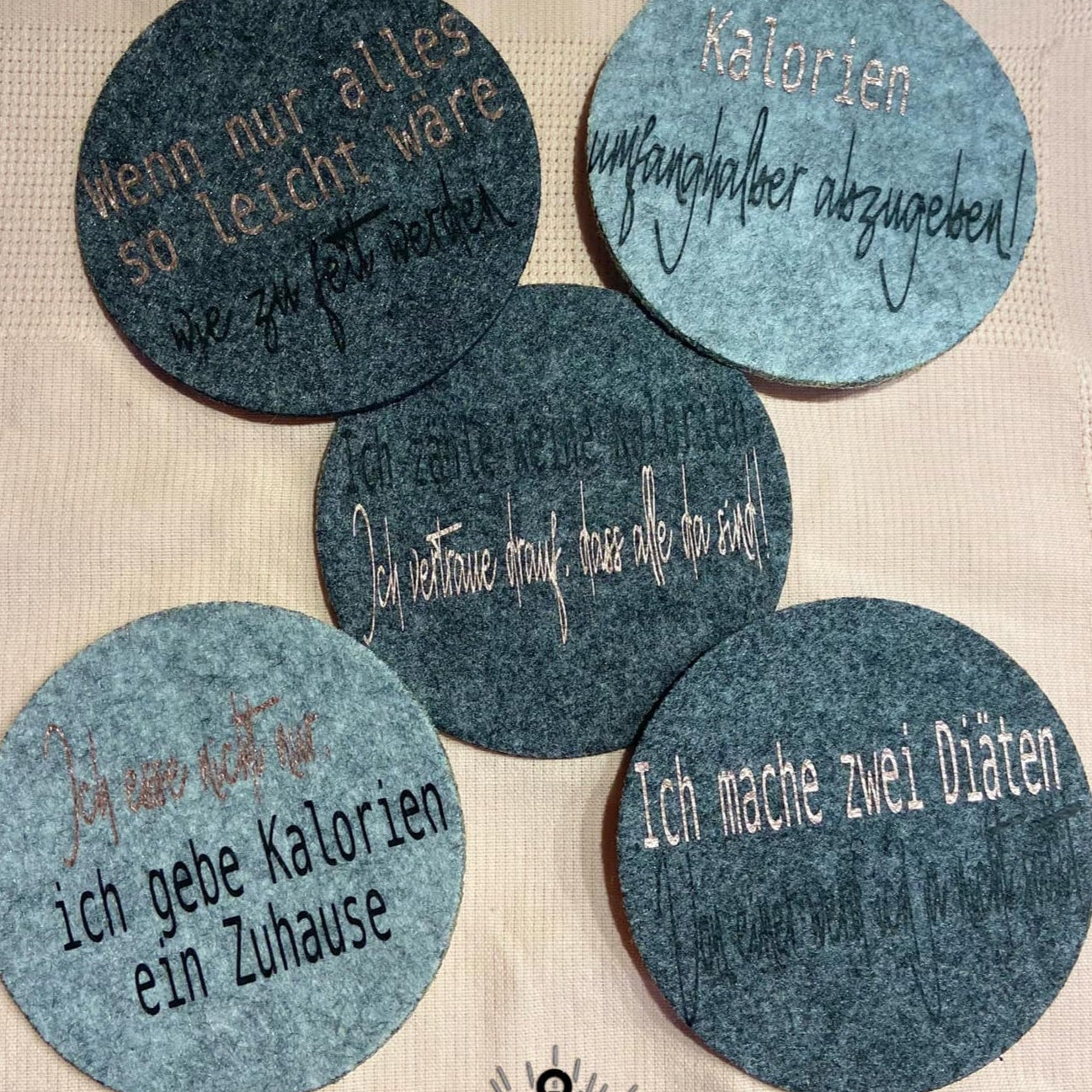 Vielseitige Kalorien Sprüche Plotterdatei von easy-sticks, abgebildet auf grauen Filzuntersetzern mit humorvollen Ausdrücken über Kalorien und Diäten.
