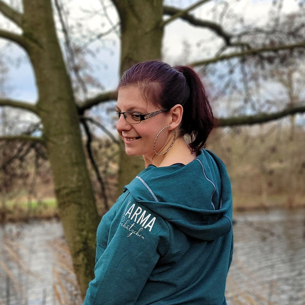 Junge Frau trägt ein aquafarbenes Hoodie mit dem Schriftzug 'KARMA Schätzchen', präsentiert von easy-sticks.