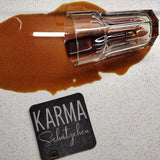 Kaffeeglas umgekippt auf einem Tisch mit dem Untersetzer 'KARMA Schätzchen', erhältlich bei easy-sticks.