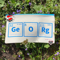 Stylische Tasche mit Elemente des Periodensystems von easy-sticks, mit blauen Symbolen auf natürlichem Stoff und lila Frühlingsblumen im Hintergrund.