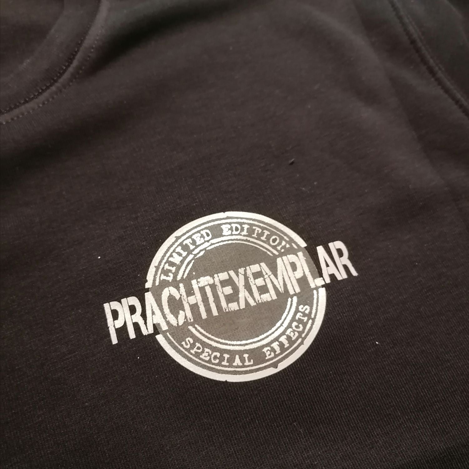 Ein Kleidungsstück (T-Shirt) in Schwarz mit dem einzigartigen 'Prachtexemplar'-Logo, das für Individualität und Stil steht, erhältlich von easy-sticks.