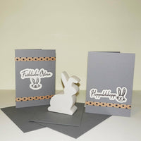 Zwei fröhliche Karten mit dem Schriftzug 'Fröhliche Ostern' und einem Hasenmotiv, umgeben von einer dekorativen Papierreihe. Die Karten sind Teil der 'Ostern - Frühling Sprüche' Plotterdatei von easy-sticks und eignen sich perfekt für kreative Projekte.