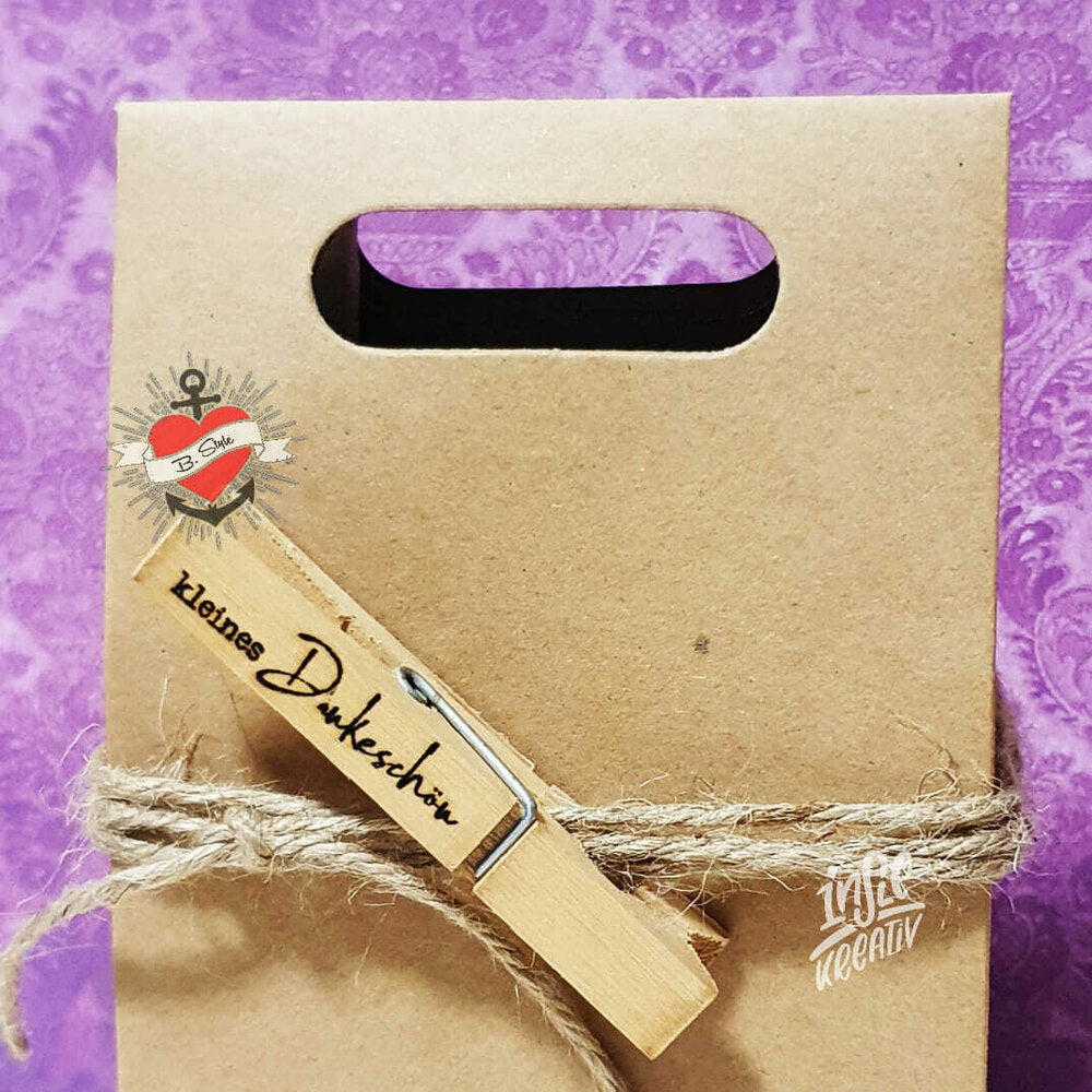 Kerzensprüche für jeden Anlass 1 von easy-sticks: Ein kreatives Geschenkpaket, das mit einer Klammer verziert ist, die den Schriftzug 'Kleines Dankeschön' trägt, präsentiert in einer braunen Geschenktüte.