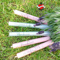 Fünf Kerzen in sanften Farben mit inspirierenden Sprüchen, umgeben von Lavendel auf grünem Gras, Kreationen, die aus der Plotterdatei "Kerzensprüche für jeden Anlass 2" von easy-sticks stammen.