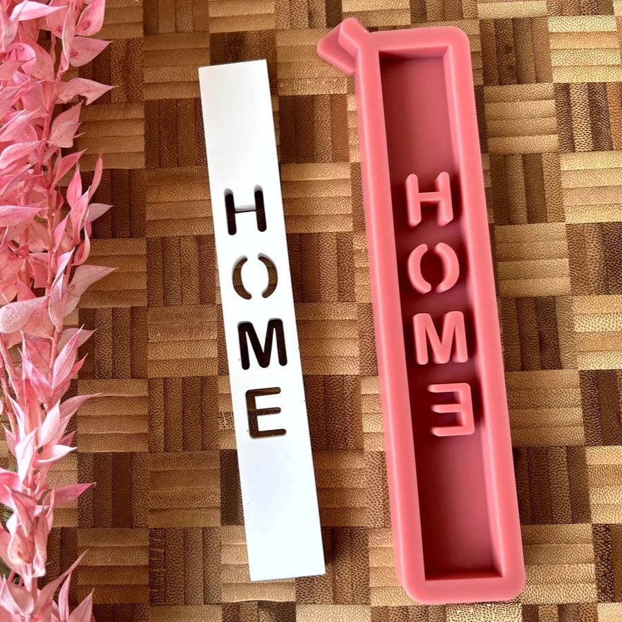 Silikonform 'HOME Schriftzug' von easy-sticks mit zwei Formen, einer weißen Form mit ausgeschnittenem Schriftzug und einer rosa Silikonform, ideal zum Gießen von Windlichtern und Dekorationen.