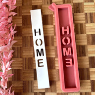 Silikonform 'HOME Schriftzug' von easy-sticks mit zwei Formen, einer weißen Form mit ausgeschnittenem Schriftzug und einer rosa Silikonform, ideal zum Gießen von Windlichtern und Dekorationen.