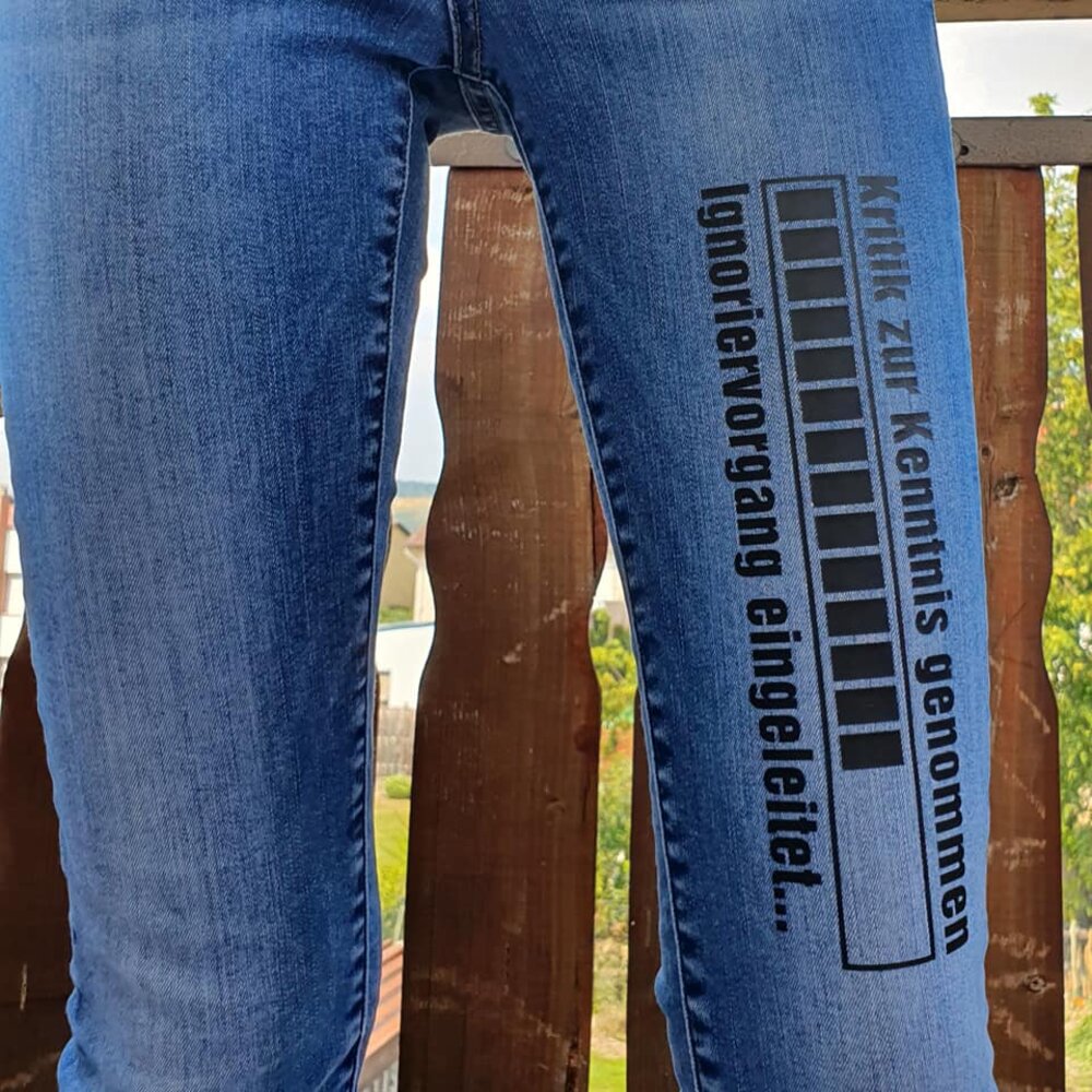 Jeans mit dem kreativen Aufdruck 'Kritik zur Kenntnis genommen ... Ignoriervorgang eingeleitet' von easy-sticks, die stilvoll getragen werden und eine einzigartige Mode-Aussage darstellen.