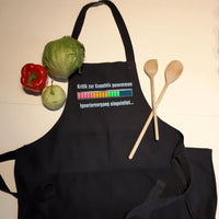Eine dunkle Kochschürze mit dem Aufdruck 'Kritik zur Kenntnis genommen ... Ignoriervorgang eingeleitet' von easy-sticks, umgeben von frischen Zutaten, darunter Gemüse und Kochlöffel.