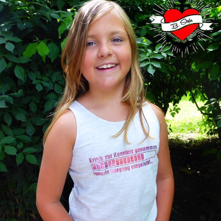 Ein fröhliches Mädchen trägt ein Tanktop mit dem Aufdruck 'Kritik zur Kenntnis genommen ... Ignoriervorgang eingeleitet' von easy-sticks in einer natürlichen Umgebung.