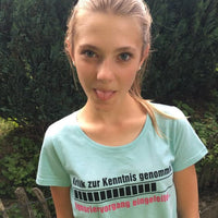 Mädchen mit frechem Gesichtsausdruck in einem hellblauen T-Shirt, das den Satz "Kritik zur Kenntnis genommen ... Ignoriervorgang eingeleitet" von easy-sticks zeigt.