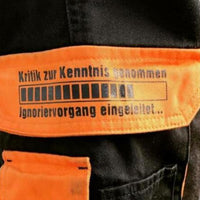 Nahaufnahme eines schwarzen Shorts mit orangefarbenem Aufdruck "Kritik zur Kenntnis genommen ... Ignoriervorgang eingeleitet" von easy-sticks.
