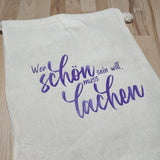 Stofftasche mit der motivationalen Botschaft 'Wer schön sein will, muss lachen', entworfen von easy-sticks, perfekt für nachhaltigen Einkauf und persönliche Projekte.