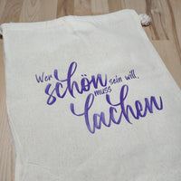 Stofftasche mit der motivationalen Botschaft 'Wer schön sein will, muss lachen', entworfen von easy-sticks, perfekt für nachhaltigen Einkauf und persönliche Projekte.