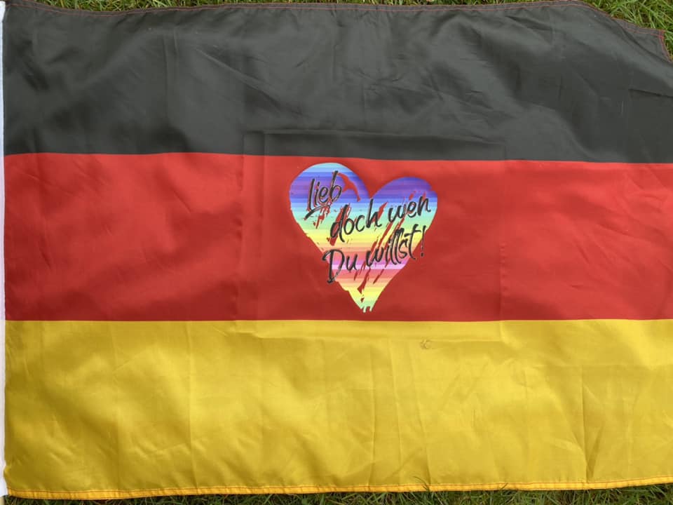 Fahne in den Farben Schwarz-Rot-Gelb, verziert mit dem Herzmotiv "Lieb doch wen du willst!", kreativ gestaltet von easy-sticks.