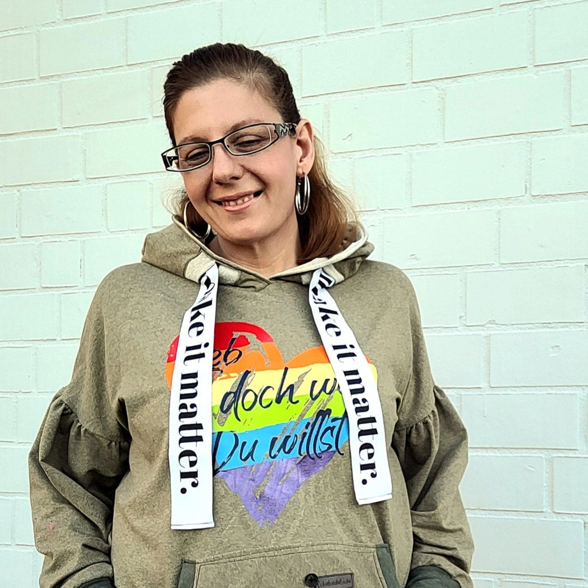 Portrait einer Frau in einem Hoodie mit dem bunten Herzen und dem Text 'Lieb doch wen du willst' von easy-sticks, stilvoll und einladend.