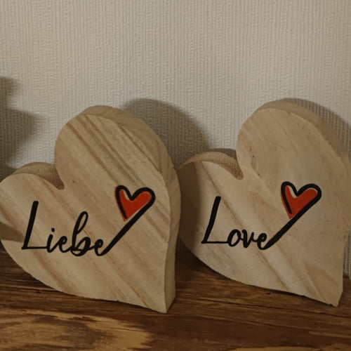 Zwei hölzerne Herzfiguren, auf denen die Worte 'Liebe' und 'Love' prangen, inspiriert von der Plotterdatei 'Liebe und Love' von easy-sticks. Ideal für romantische Deko.