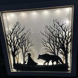 Leuchtendes Deko-Glasbild mit dem Motiv "Märchen Rotkäppchen und der böse Wolf" von easy-sticks, zeigt eine Silhouette von Rotkäppchen und dem Wolf vor einer Baumlandschaft.