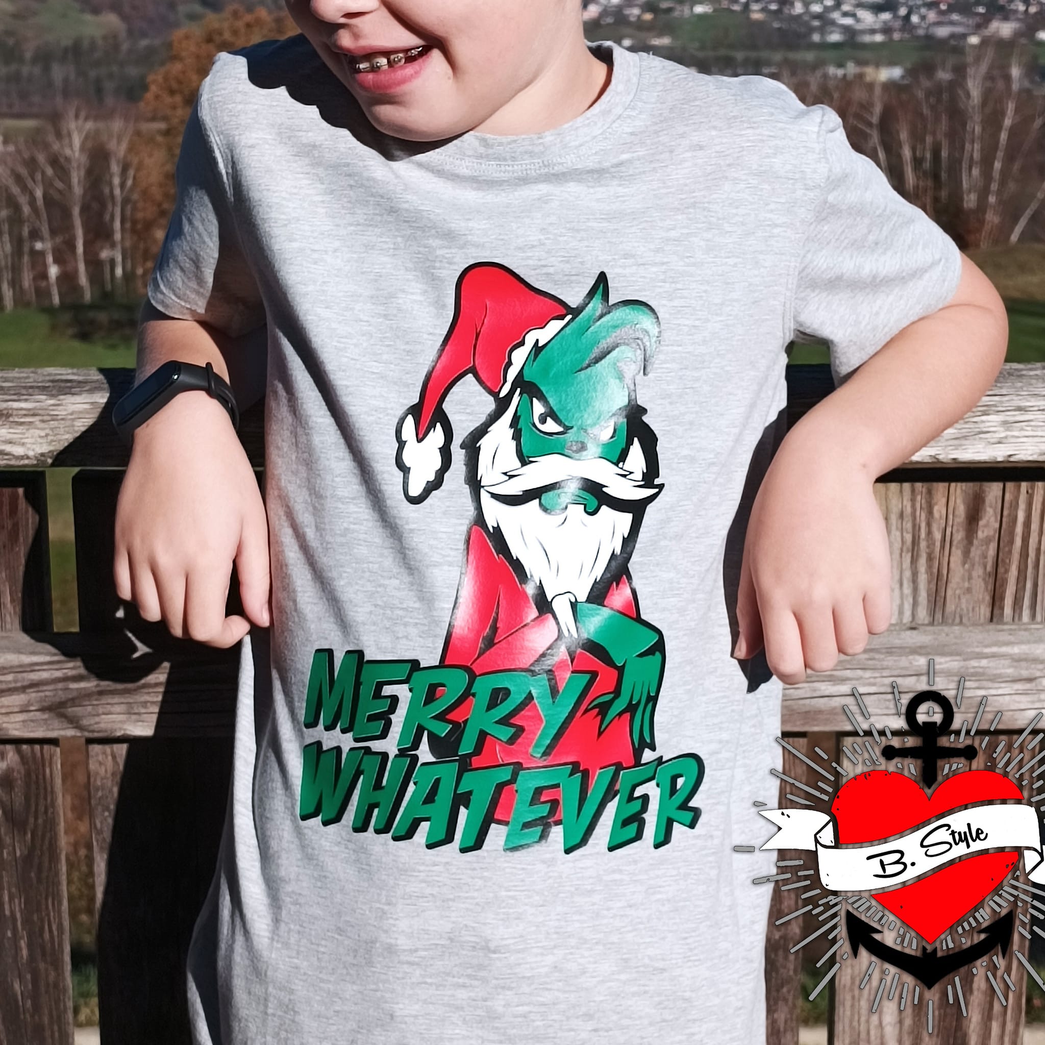 Ein Junge trägt ein graues T-Shirt mit dem Aufdruck 'Merry Whatever' und einem humorvollen Charakter. Ideal für kreative Designs und Bastelideen mit der Plotterdatei von easy-sticks.