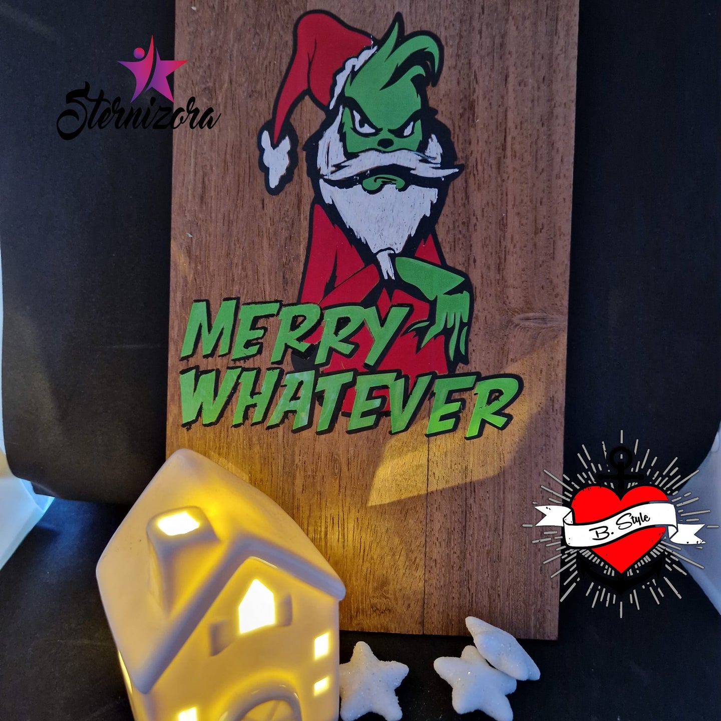 Holzschild mit einer farbenfrohen Darstellung eines grünen Charakters im Weihnachtsmann-Outfit, der vor einer sanften Beleuchtung steht. Eine großartige Anwendung für die "Merry Whatever" Plotterdatei von easy-sticks.