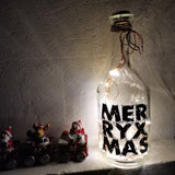 Dekorative Glasflasche mit Lichtern und dem Schriftzug 'MERRY X MAS', gestaltet mit der 'Merry X Mas' Plotterdatei von easy-sticks, ideal für festliche Kreativprojekte.