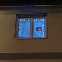 Fenster mit festlicher Beleuchtung und dem Schriftzug 'MERRY X MAS', dekoriert mit der 'Merry X Mas' Plotterdatei von easy-sticks für kreative Weihnachtsprojekte.