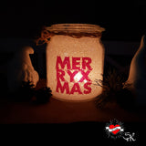 Ein glitzerndes Glasgefäß mit dem Schriftzug "MERRY X MAS", das mit sanftem Licht erleuchtet wird und eine gemütliche Atmosphäre schafft, entworfen mit der "Merry X Mas" Plotterdatei von easy-sticks.