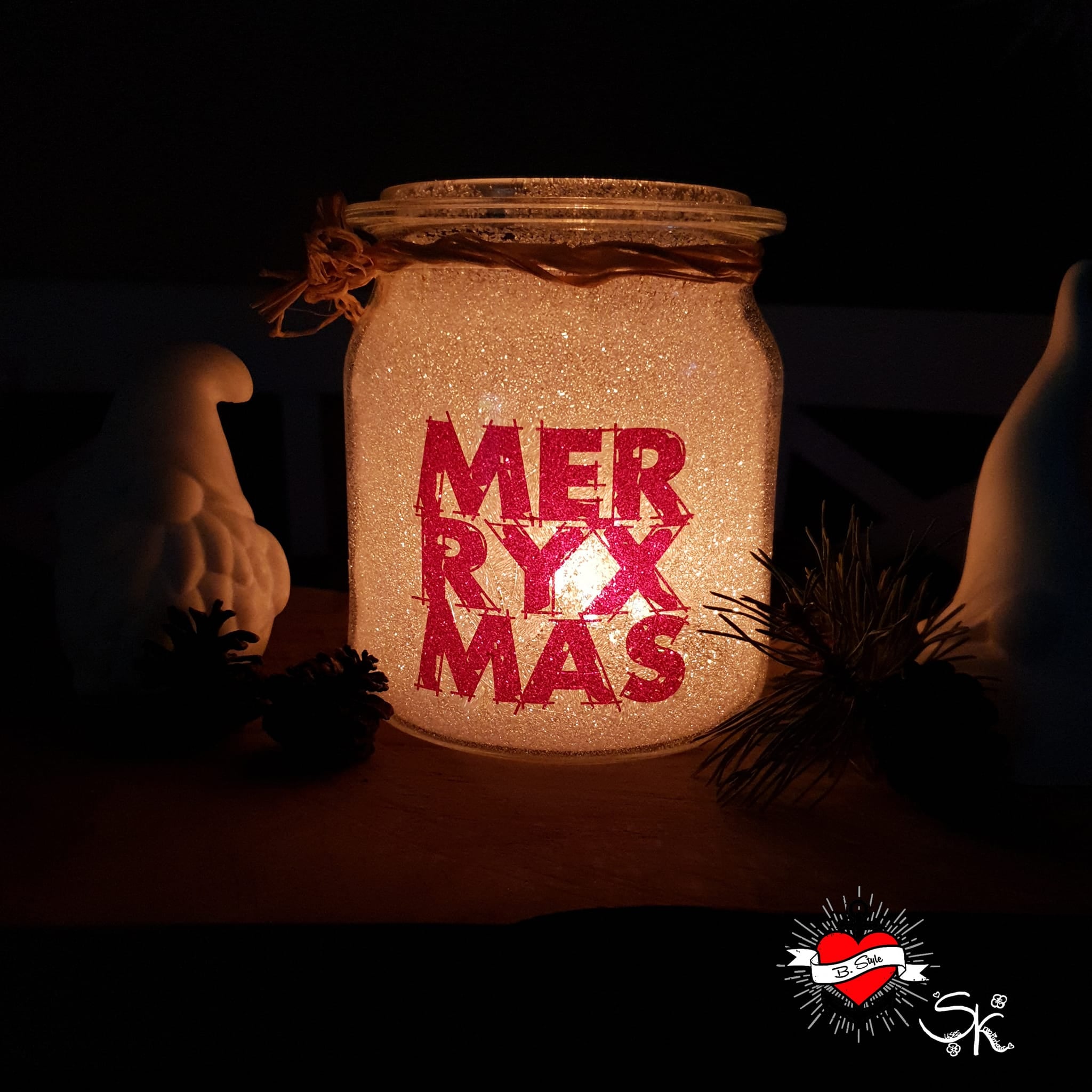Ein glitzerndes Glasgefäß mit dem Schriftzug "MERRY X MAS", das mit sanftem Licht erleuchtet wird und eine gemütliche Atmosphäre schafft, entworfen mit der "Merry X Mas" Plotterdatei von easy-sticks.