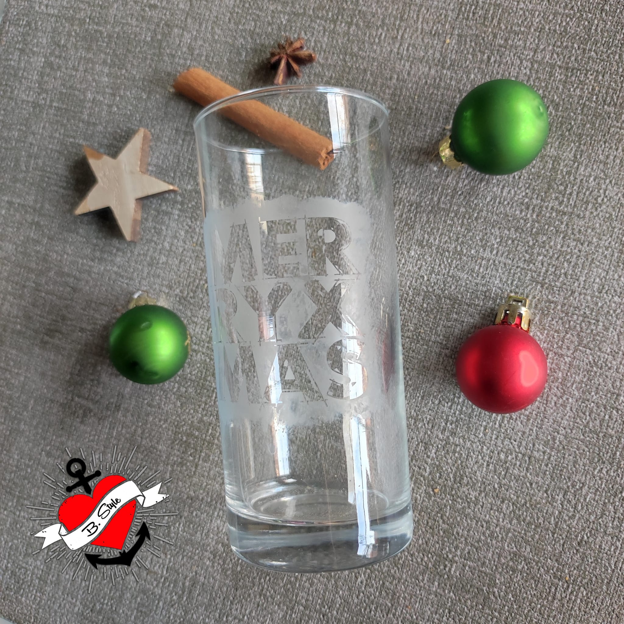 Elegantes Glaskrug-Design, das die 'Merry X Mas' Plotterdatei von easy-sticks zeigt, umgeben von Weihnachtsdekoration, ideal für Weihnachten.