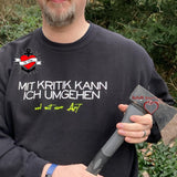 Mann trägt ein schwarzes Sweatshirt mit dem provokanten Text "Mit Kritik kann ich umgehen - und mit einer Axt", erstellt von easy-sticks und inspiriert von der Plotterdatei.