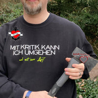 Mann trägt ein schwarzes Sweatshirt mit dem provokanten Text "Mit Kritik kann ich umgehen - und mit einer Axt", erstellt von easy-sticks und inspiriert von der Plotterdatei.