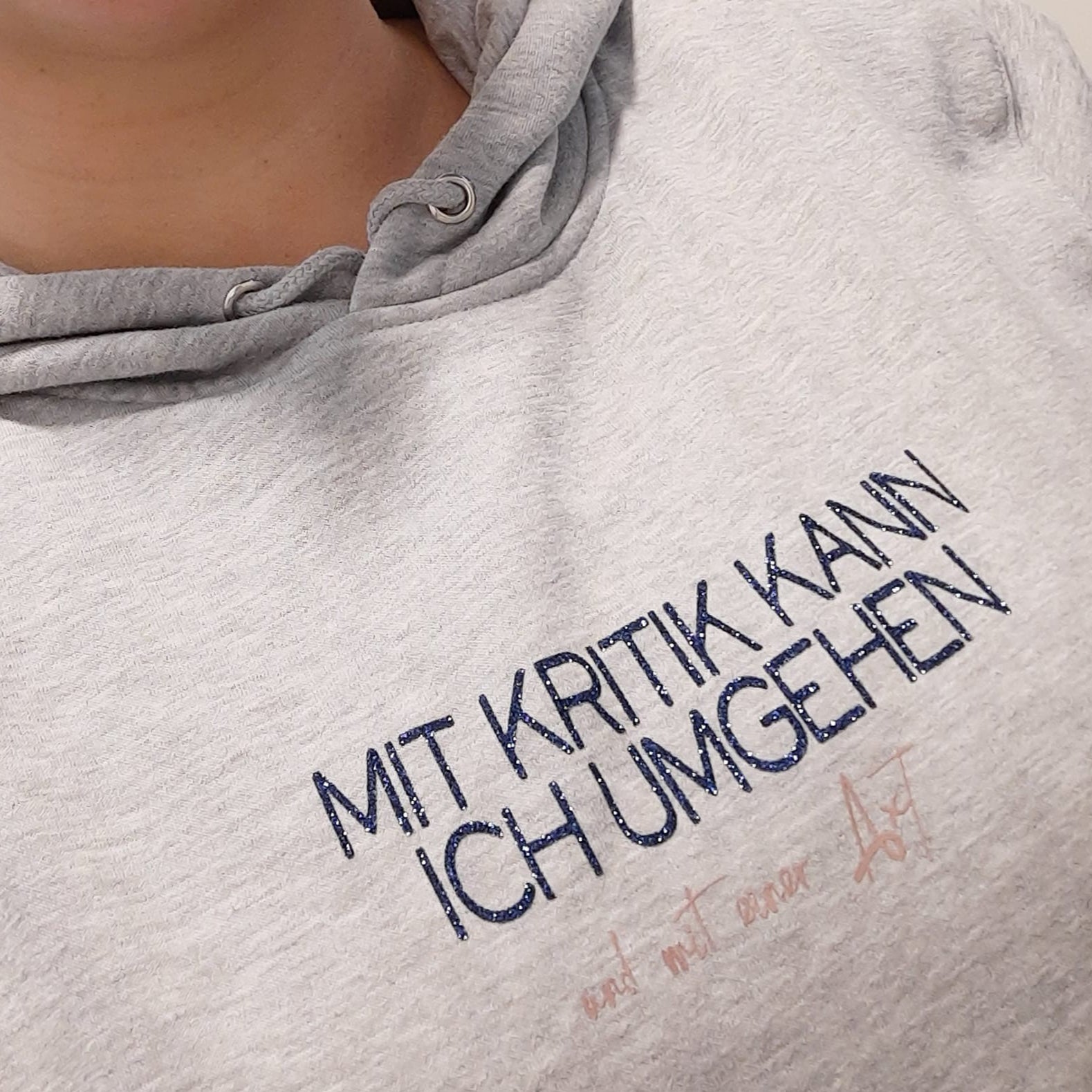 Gemütlicher Hoodie in Grautönen, verziert mit dem Spruch "Mit Kritik kann ich umgehen - und mit einer Axt", einem Design von easy-sticks basierend auf der Plotterdatei.