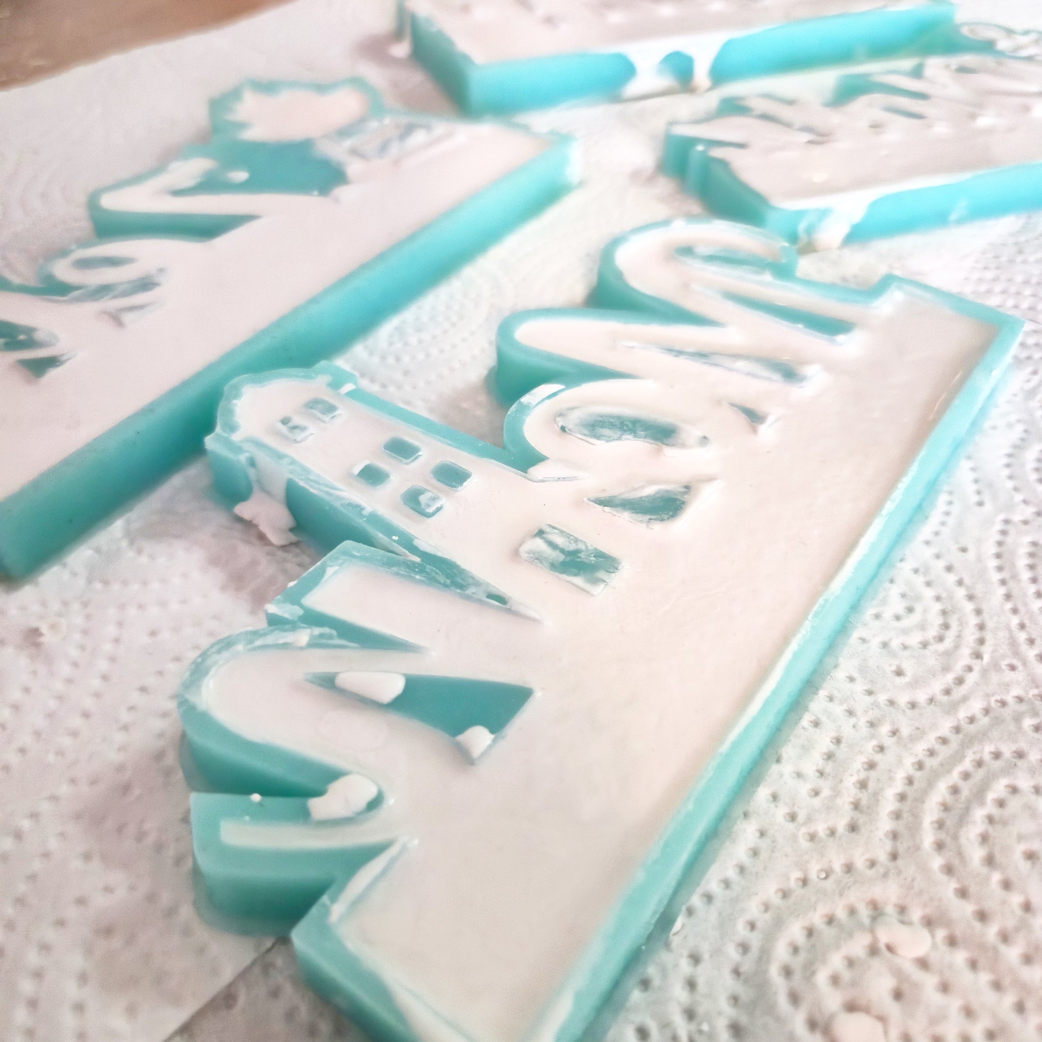 Easy-Sticks Einschieber Silikonform - Moin Leuchtturm mit detailliert gegossenen Buchstaben in Pastellfarben auf einem Küchenpapier, ideal für kreative DIY-Projekte.