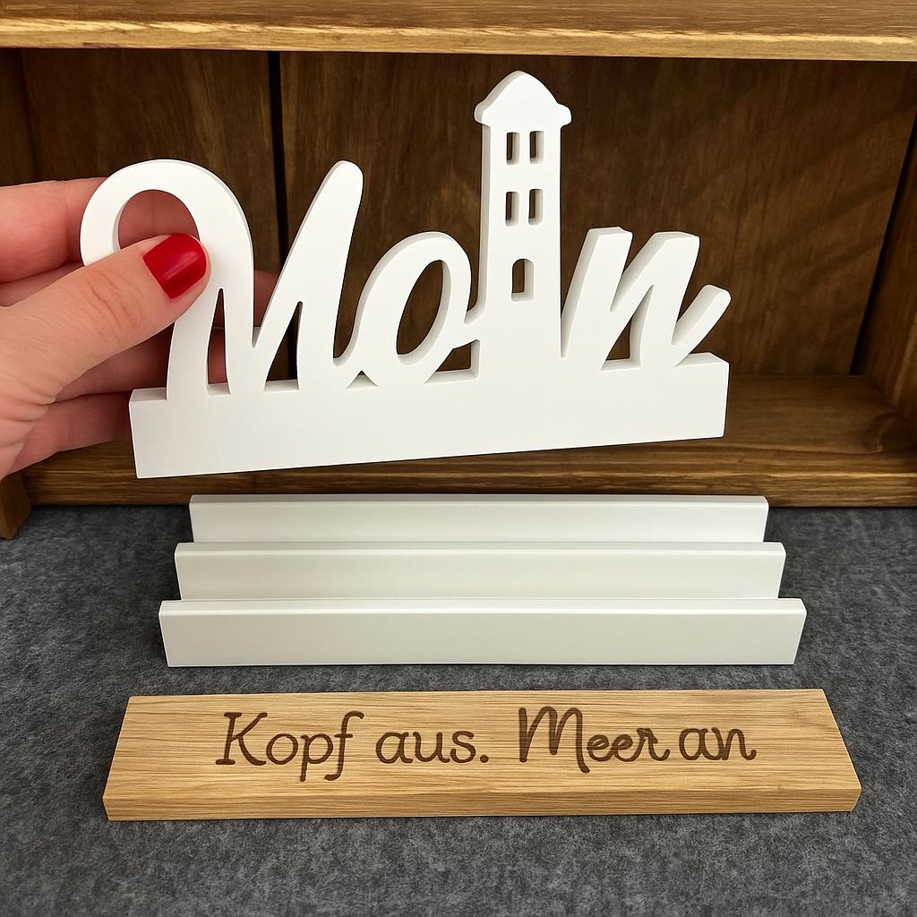 Easy-Sticks Einschieber Silikonform - Moin Leuchtturm, ein Handmodell zeigt den weißen Schriftzug 'Moin' vor einer Holzablage mit einer persönlichen Botschaft.