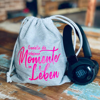 Beutel mit dem kreativen Design 'Genieße die schönen Momente im Leben' von easy-sticks, ergänzt durch modernes Headset auf einem rustikalen Holztisch.