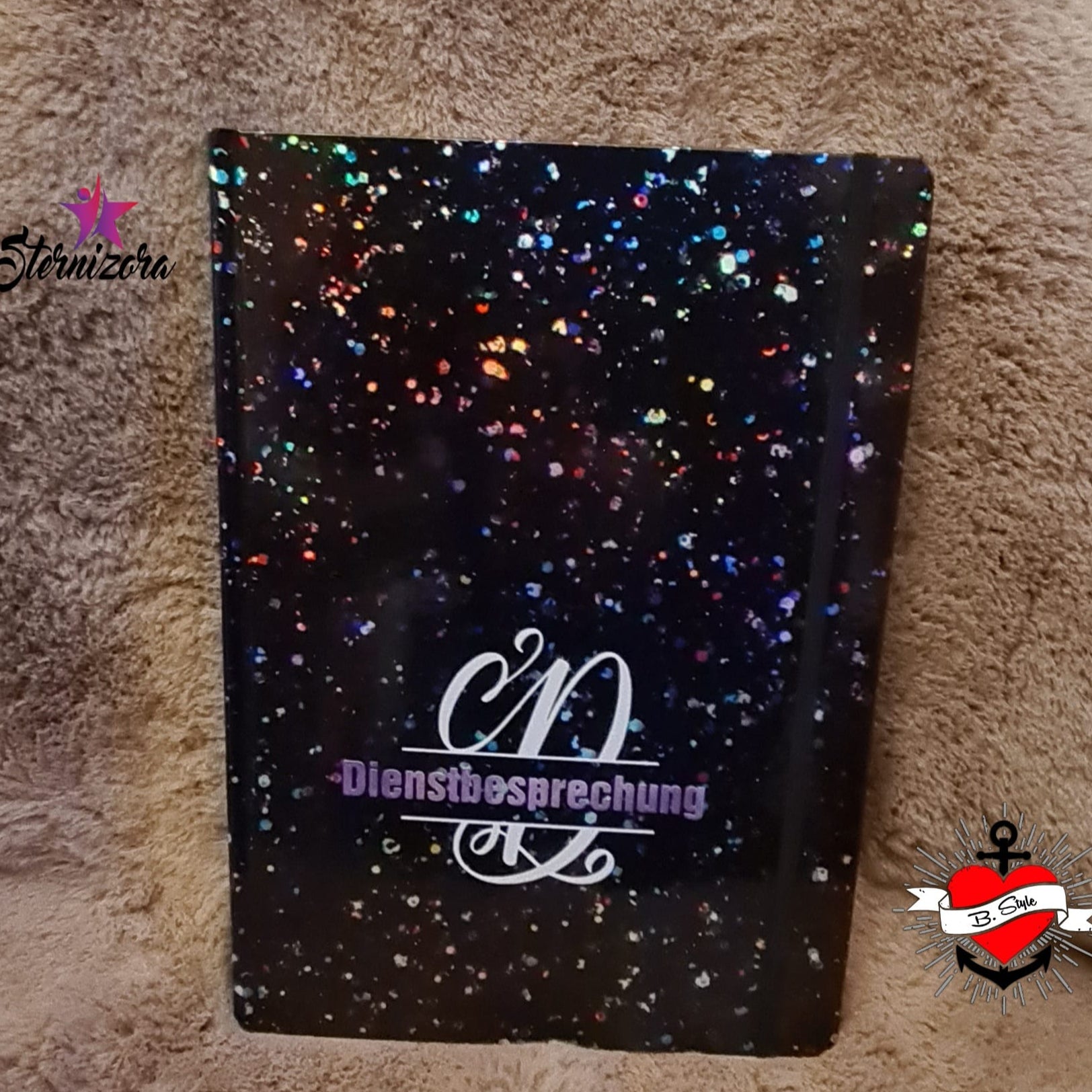 Funky und bunte Monogramm 'D' Plotterdatei von easy-sticks, ideal für kreative DIY-Projekte, abgebildet auf einer funkelnden schwarzen Notizbuchhülle mit Glitzer.