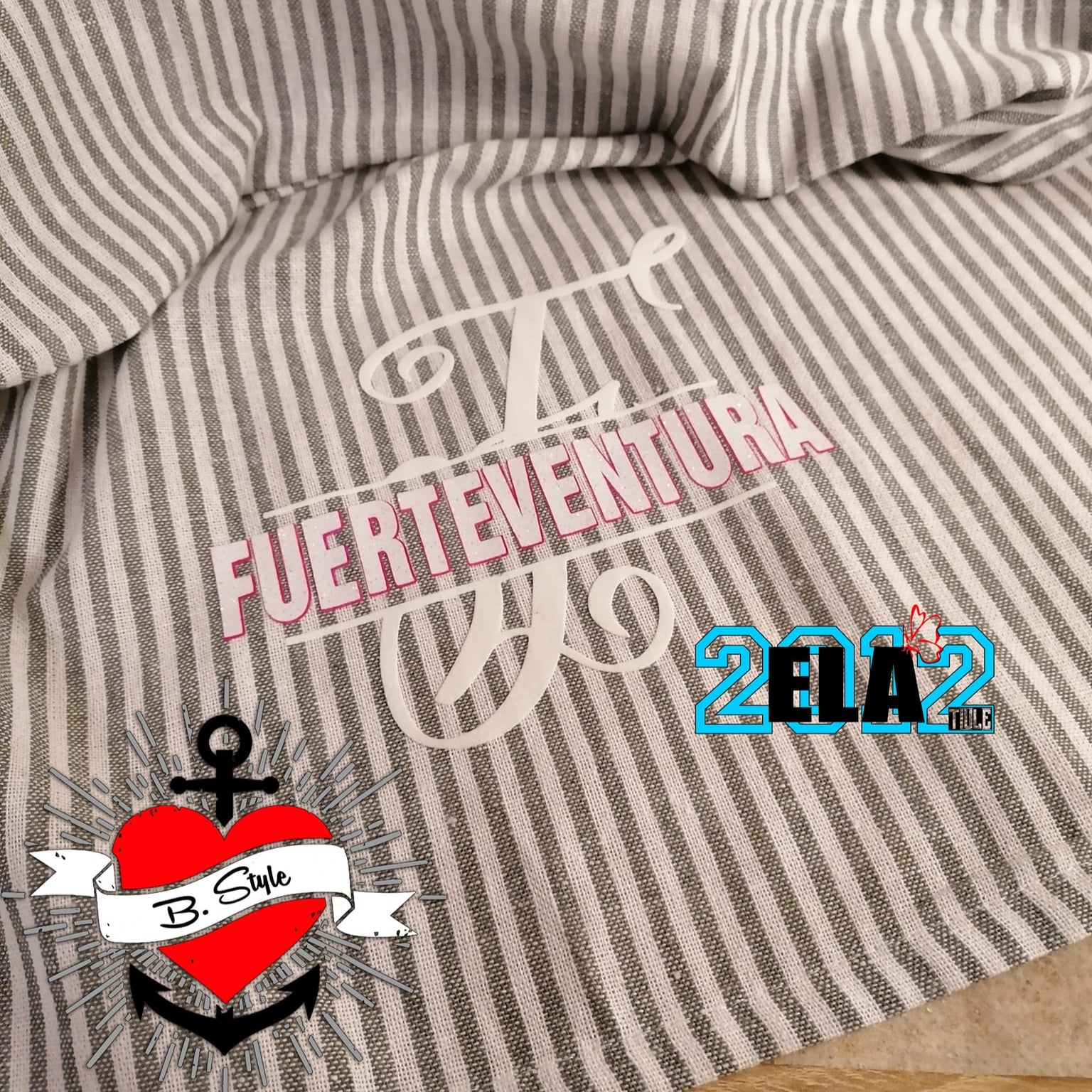 Kreative Stoffgestaltung mit der Monogramm 'F' Plotterdatei von easy-sticks, wo 'FUERTEVENTURA' stilvoll in pinker Schrift auf einem gestreiften Hintergrund zur Geltung kommt.