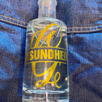 Eine Flasche mit einem Aufkleber, der das Wort 'GESUNDHEIT' zusammen mit dem Monogram 'G' anzeigt. Ideal für kreative Geschenkideen, entworfen mit der Monogram 'G' Plotterdatei von easy-sticks.