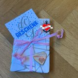 Ein kreativ verpacktes Geschenk mit einer Karte mit der Aufschrift 'GESCHENK', verziert mit einer pinken Schleife. Ideal für DIY-Projekte mit der Monogram 'G' Plotterdatei von easy-sticks.