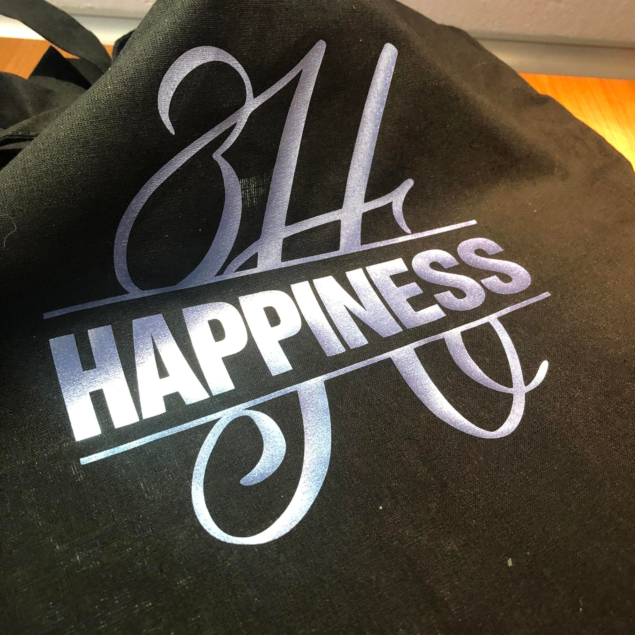 Monogramm 'H' Plotterdatei von easy-sticks auf einer schwarzen Tragetasche, die das Wort 'HAPPINESS' elegant inszeniert.