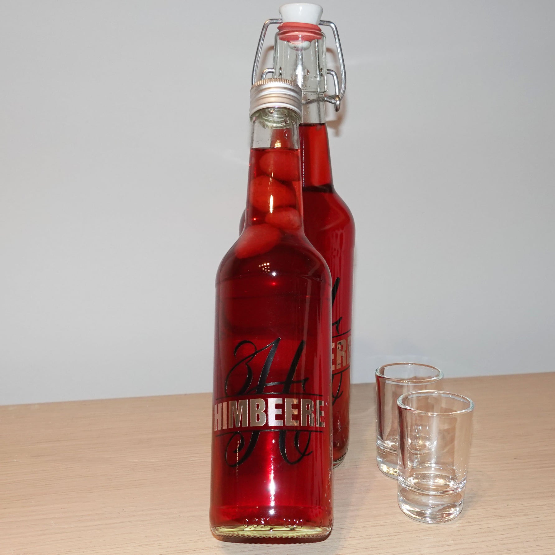 Zwei Flaschen mit rotem Getränk, verziert mit dem Monogramm "H" und der Aufschrift 'HIMBEERE', ein kreatives Produkt von easy-sticks, inspiriert durch die Monogram "H" Plotterdatei.