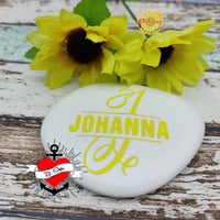 Kreatives Beispiel für die Monogram "J" Plotterdatei von easy-sticks, präsentiert auf einem weißen Stein mit gelbem Design und Sonnenblumen im Hintergrund.